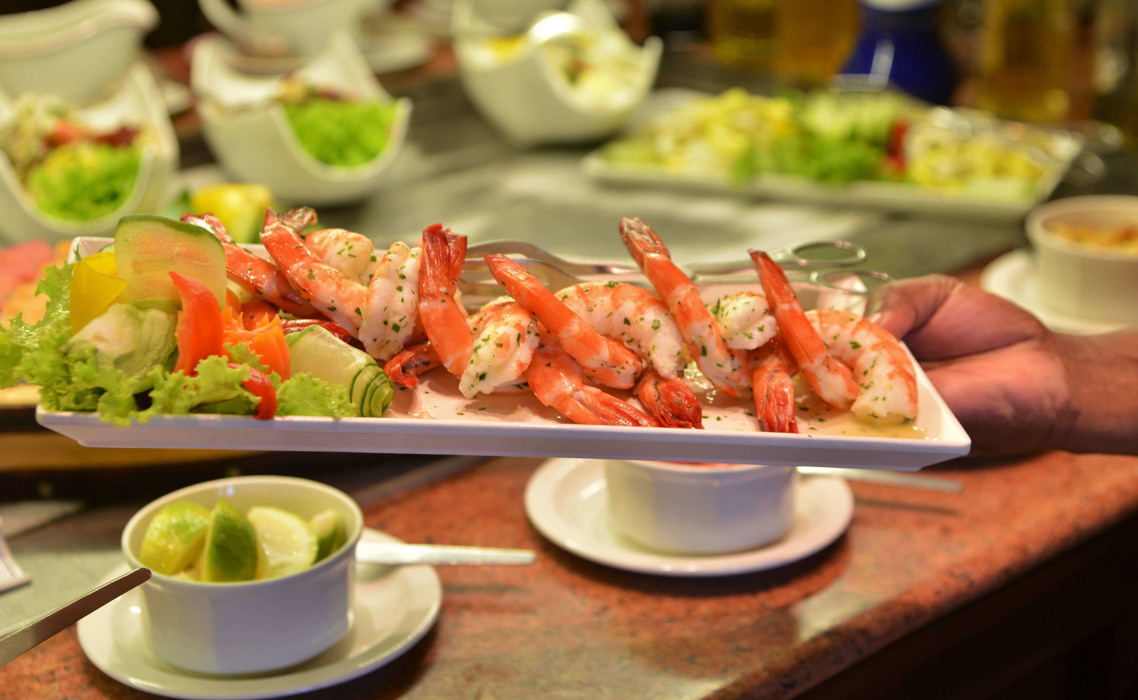 Un plato de camarones con vegetales sobre una bandeja blanca.