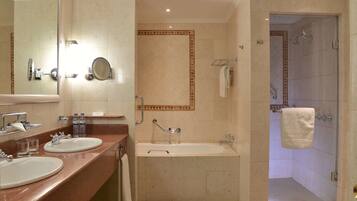 A bathroom with two sinks, a bathtub, and a shower.