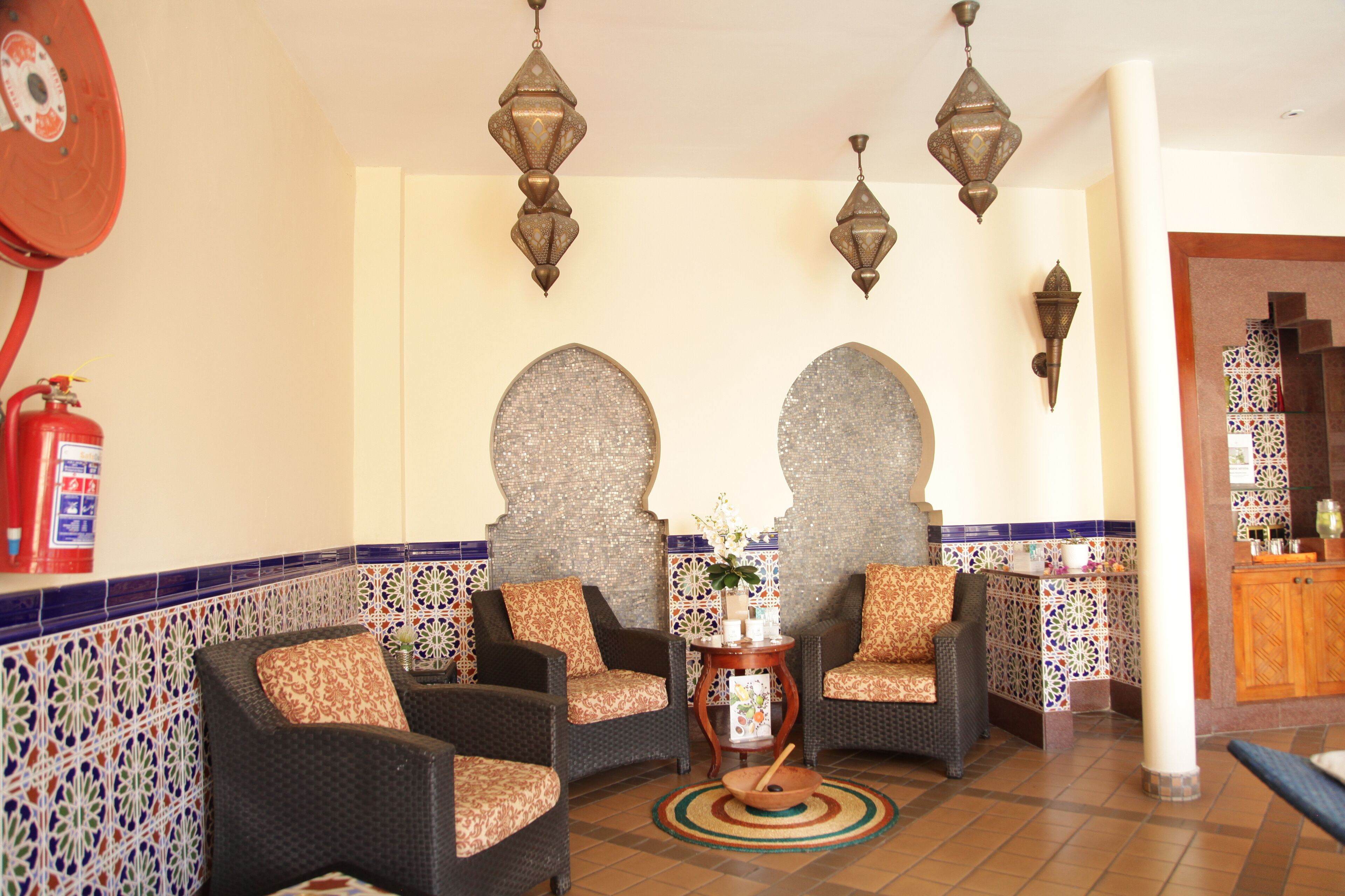 A lobby with two sofas, a small table with a bowl, and a fire extinguisher.