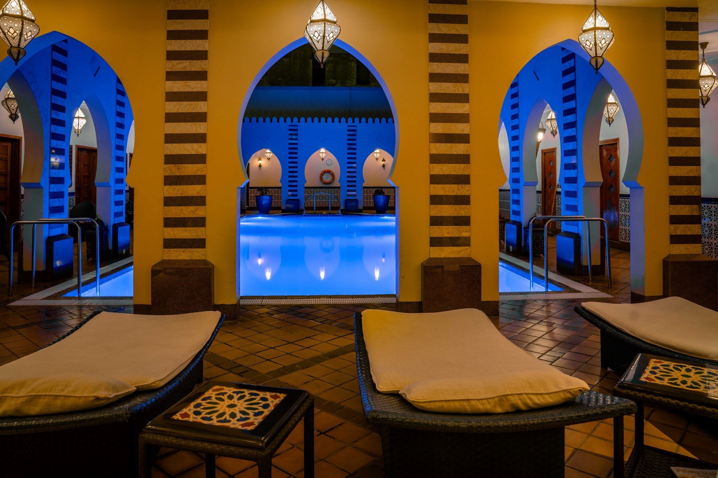 A spa area with a pool, arched alcoves, and lounge chairs.