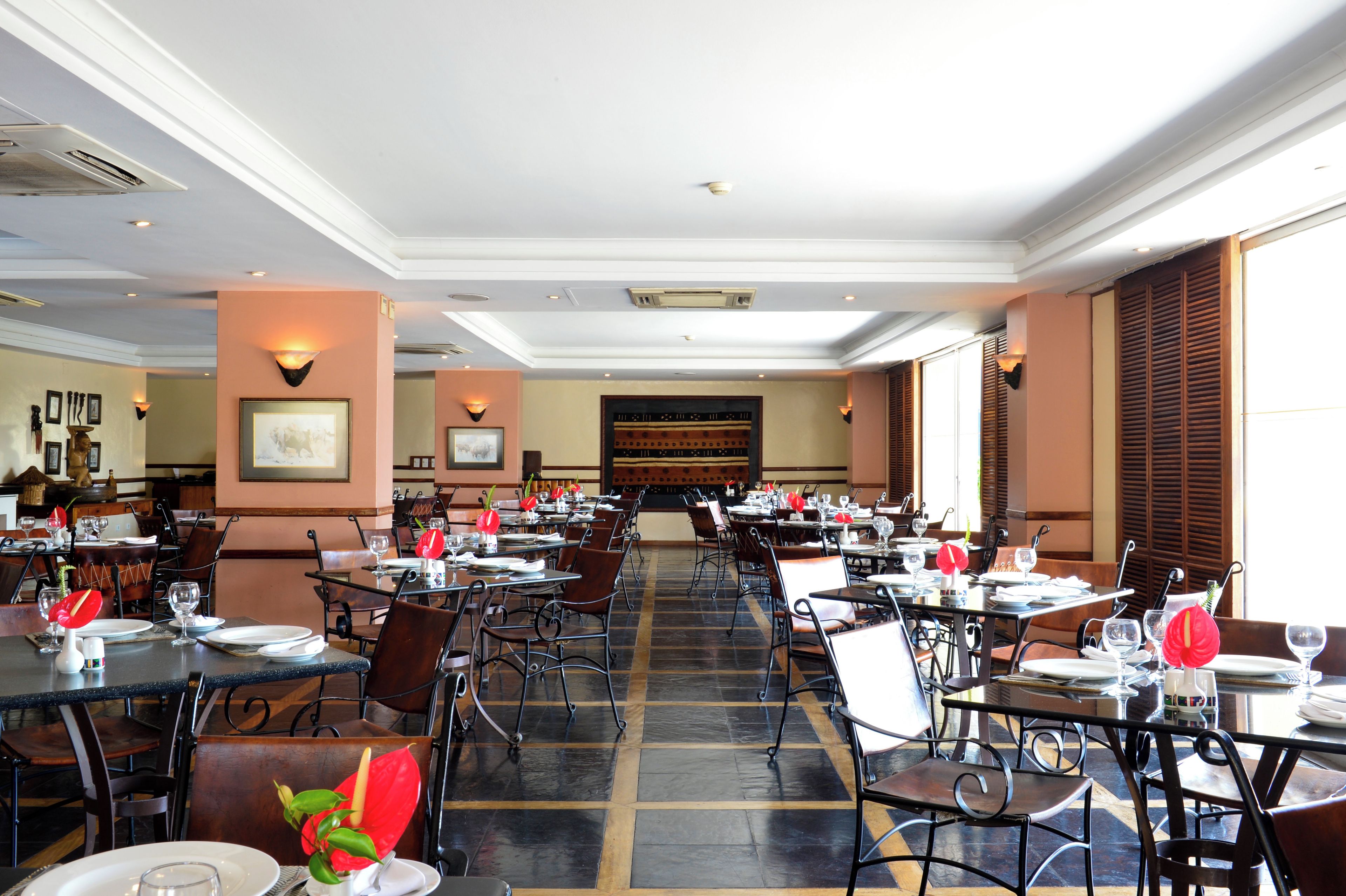 A spacious restaurant with multiple tables and chairs, a patterned floor, and framed artwork on the walls.