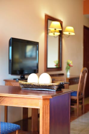 Una habitación de hotel con una mesa de madera, un televisor y una lámpara.