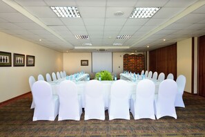 A conference room with a long table, white chairs, and water bottles.