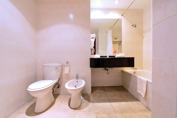 Un baño con inodoro, bidé, lavabo y bañera.