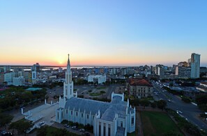 Un paisaje urbano con una iglesia destacada, que cuenta con una aguja alta, rodeada de edificios modernos y un cielo despejado.