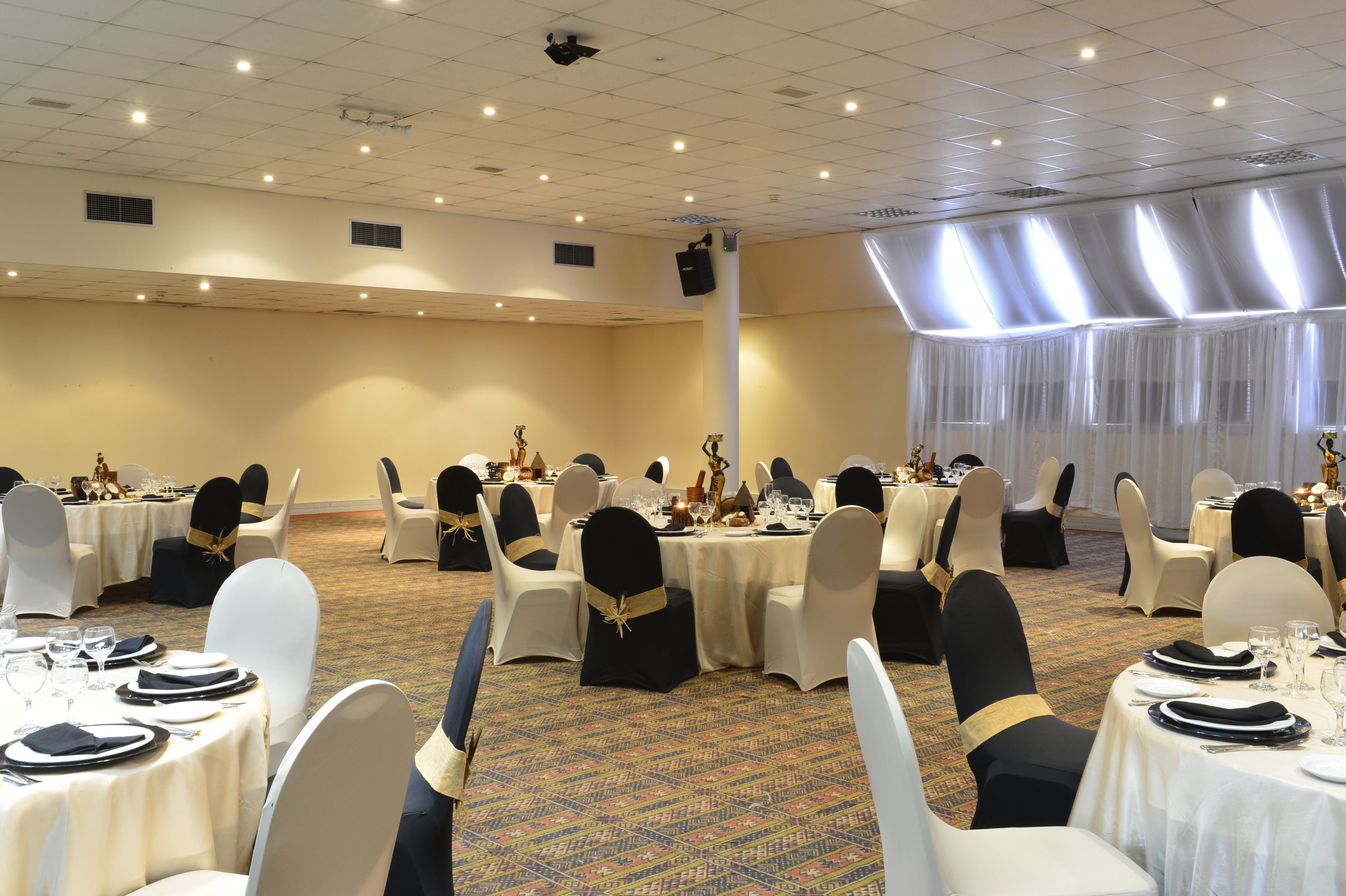 A banquet hall with round tables, chairs, and a carpeted floor.