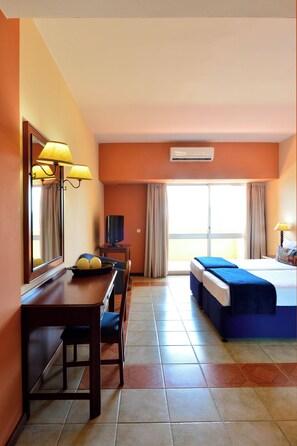 A hotel room with a bed, a desk, a television, and a window with curtains.