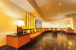 Un vestíbulo moderno con una zona de estar curva, un mostrador de recepción y una lámpara fijada a la pared.
