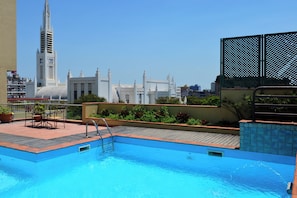 A rooftop pool with a view of a city skyline, including a tall tower with a clock. - Pestana Rovuma (Maputo)
