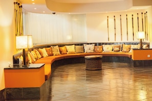 A modern lobby with a curved seating area, a small round table, and a wall with vertical light fixtures. - Pestana Rovuma (Maputo)