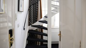 Un escalier recouvert d’une moquette à motifs, avec une main courante et une porte dotée d’une poignée en laiton.