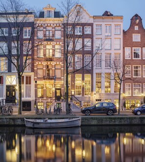 A row of historic buildings with a canal in the foreground, reflecting the architecture. - Ambassade Hotel (Amsterdam)
