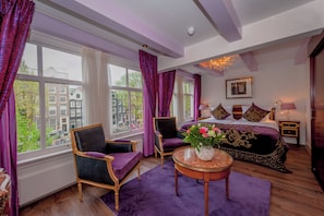 Relax in a classic hotel room with a large bed, seating area, and city views.