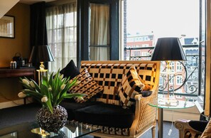 A checkered sofa with black and white cushions, a glass table with a lamp, and a potted plant with white flowers.