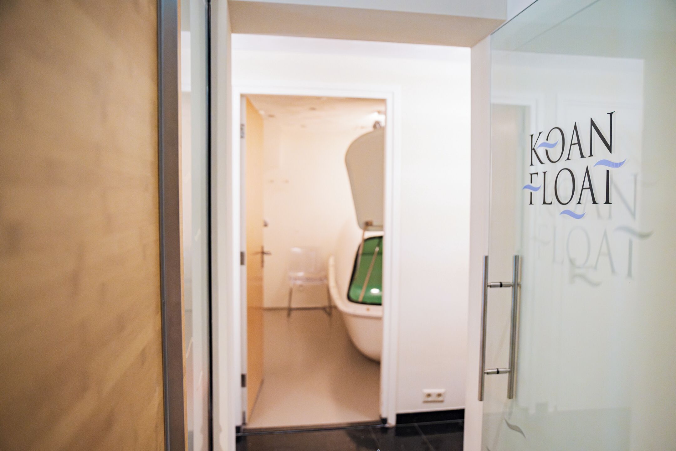 Un baño moderno con una puerta de cristal que muestra la etiqueta 'KOAN FLOAT'.