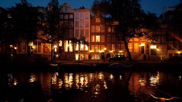 A nighttime view of a canal with buildings on one side and trees on the other.