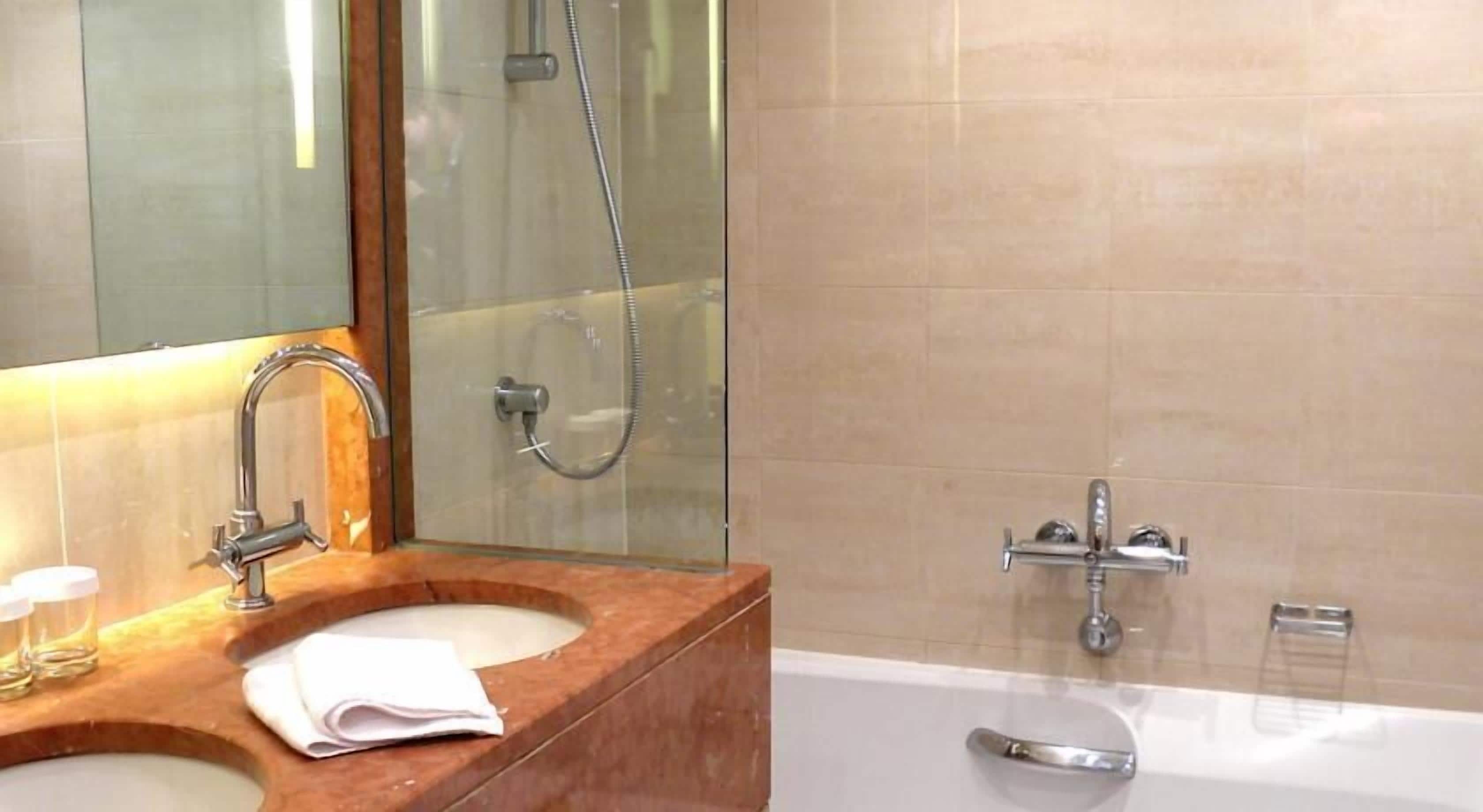 A bathroom with a wooden vanity, a large mirror, a bathtub, and a shower.