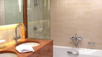 A bathroom with a wooden vanity, a large mirror, a bathtub, and a shower.