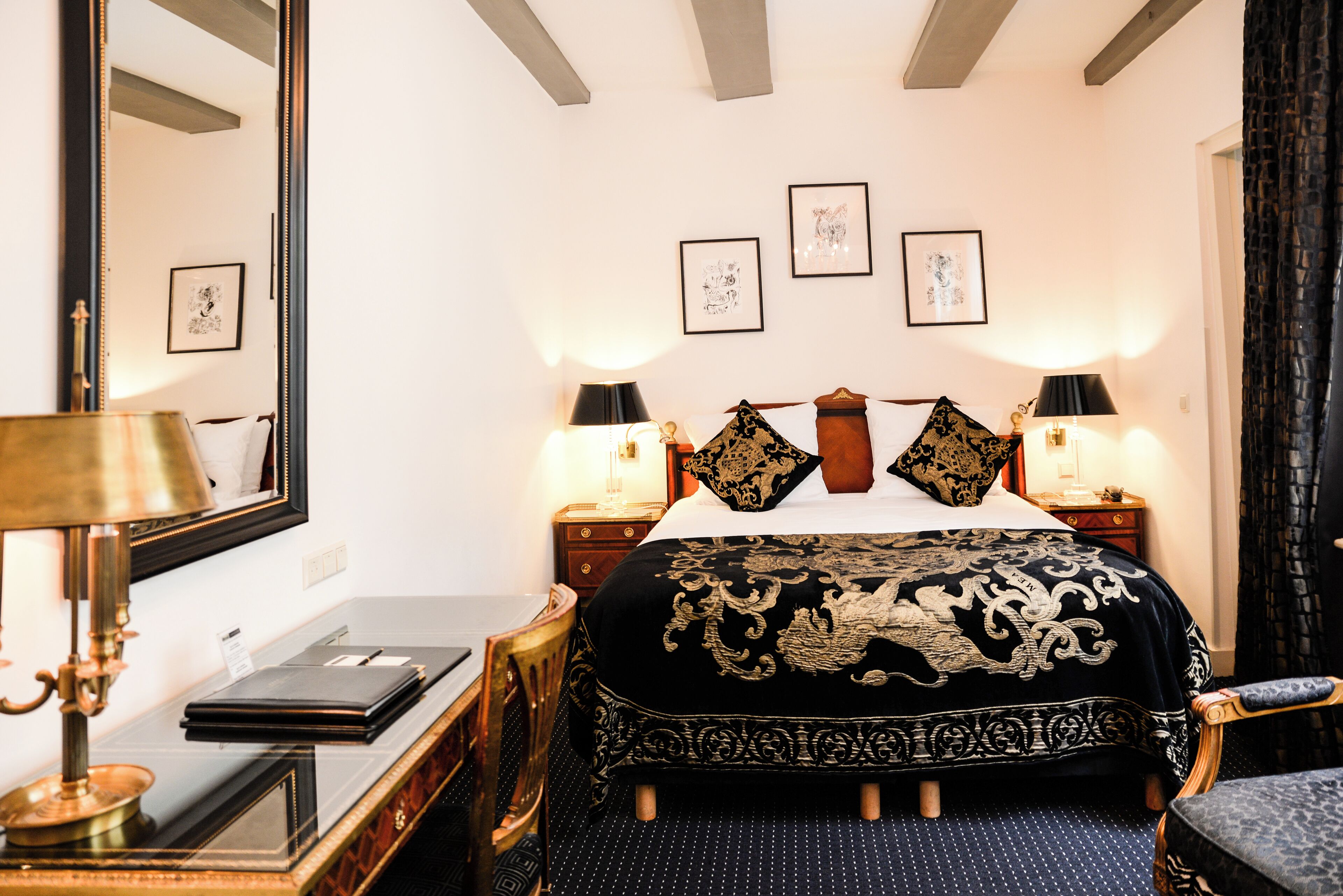 Habitación de hotel con una cama grande, dos mesitas de noche, un escritorio con lámpara y una silla.