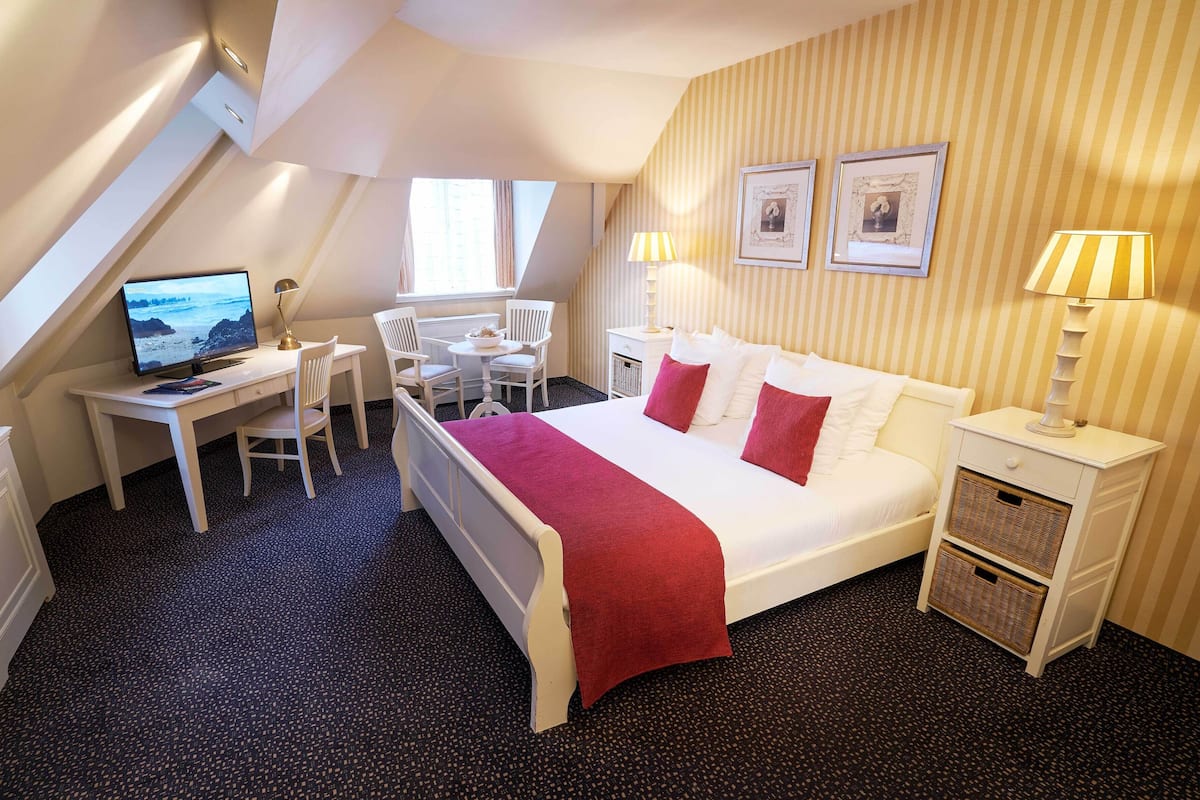 Een hotelkamer met een bed, bureau, stoel, een televisie en een raam.