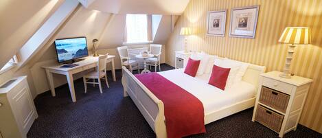Habitación de hotel con cama, escritorio, silla, televisor y ventana.