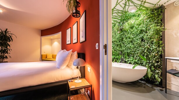 A modern bedroom with a large bed, bedside table, and a wall-mounted plant wall. - Gooiland Hotel (Hilversum)