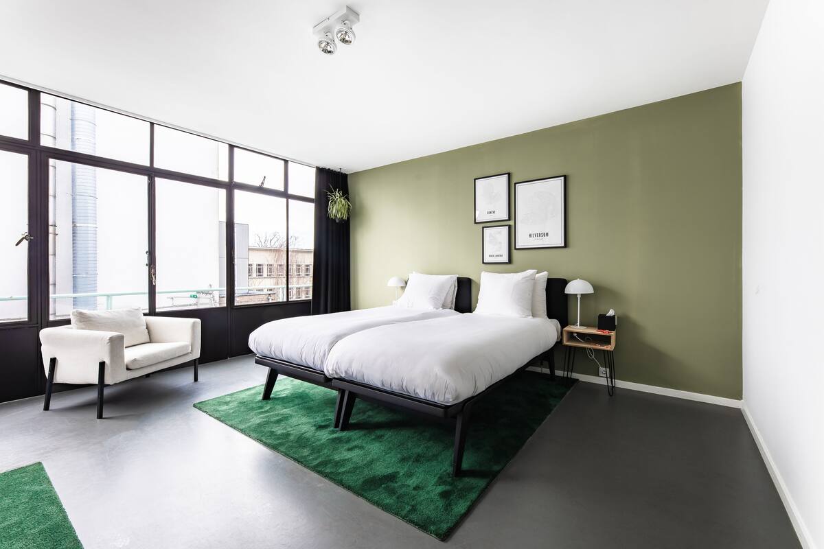 A modern bedroom with a large bed, a sofa, and a desk.