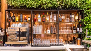 A bar area with a variety of liquor bottles, a Nespresso machine, and neatly arranged glasses. - Gooiland Hotel (Hilversum)