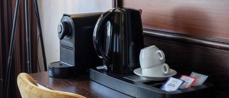 Habitación de hotel con cafetera, taza y bandeja con tarjetas de desayuno sobre una mesa de madera.
