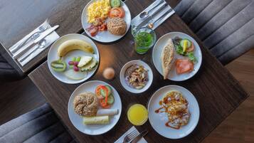 Ein Tisch mit verschiedenen Frühstücksangeboten, darunter Eier, Speck, Toast und einem Obstsalat.