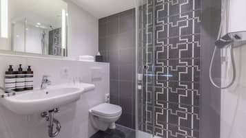 A modern bathroom with a glass-enclosed shower, a white sink, and a toilet.