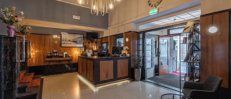 A hotel lobby with a reception desk, seating area, and a clock on the wall.