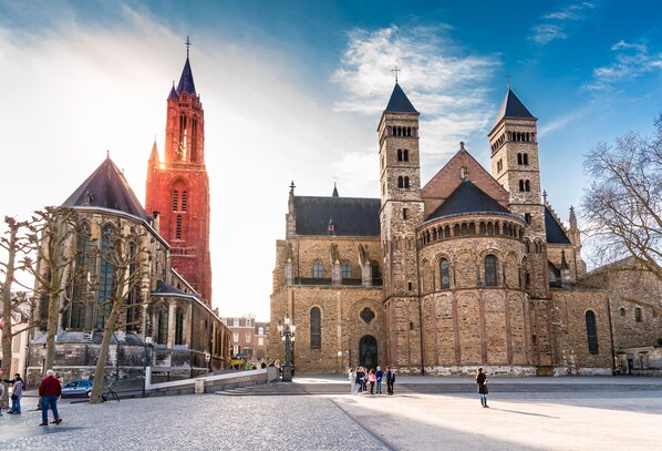 A historic church with two prominent towers and a large dome, situated in a public square with cobblestone pavement. - Amrâth Hotel DuCasque (Maastricht)