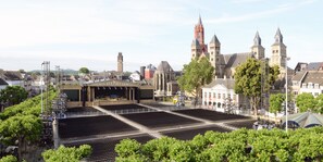 A large outdoor amphitheater with tiered seating, surrounded by trees and historic buildings with towers. - Amrâth Hotel DuCasque (Maastricht)