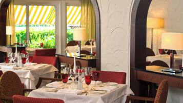Un restaurante con mesas dispuestas para comer, con sillas rojas y manteles blancos.
