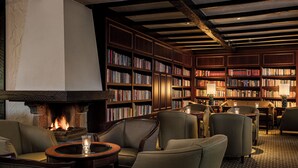 A cozy library with bookshelves, comfortable seating, and a fireplace. - Fletcher Parkhotel De Wiemsel (Ootmarsum)