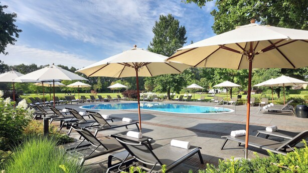 A poolside area with lounge chairs and umbrellas. - Fletcher Parkhotel De Wiemsel (Ootmarsum)