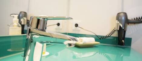 A modern bathroom with a chrome faucet, a green sink, and a hairdryer on the counter.