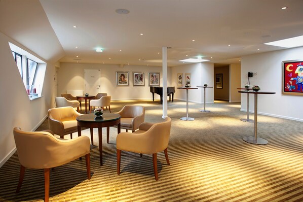 A hotel lobby with a carpeted floor, several chairs, a piano, and framed artwork on the walls. - Fletcher Parkhotel De Wiemsel (Ootmarsum)