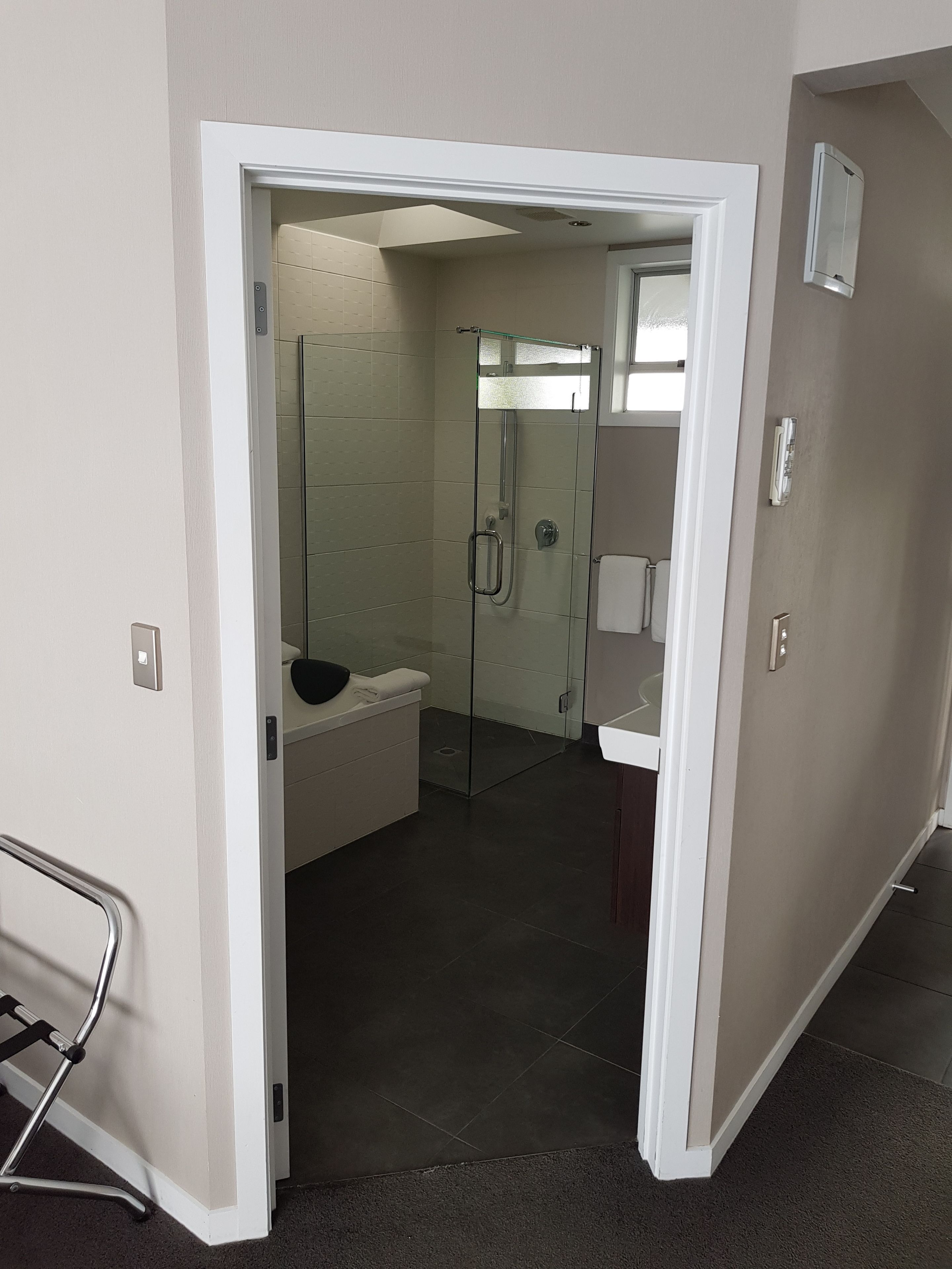 A bathroom with a glass shower enclosure, a white sink, and a towel rack.