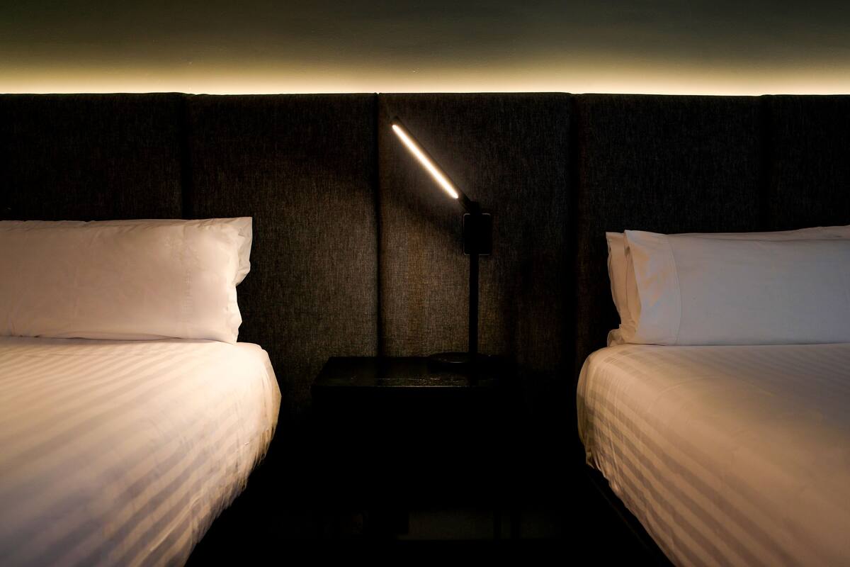 Een hotelkamer met twee bedden, een nachtkastje en een wandlamp voor het lezen.