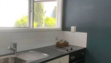 A kitchen with white cabinets, a black countertop, a sink, and a window.