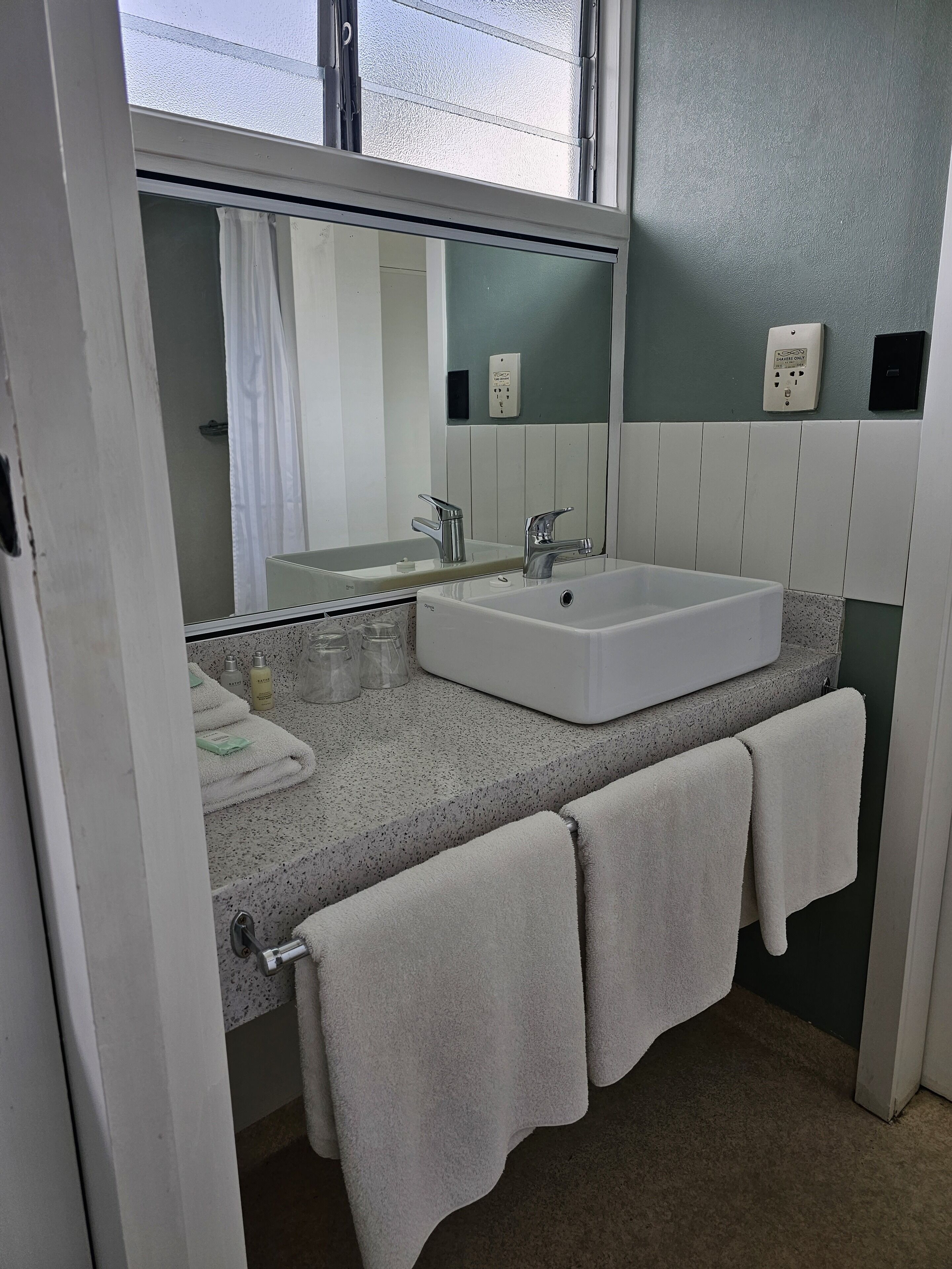 A bathroom with a white sink, a mirror, and a towel rack.