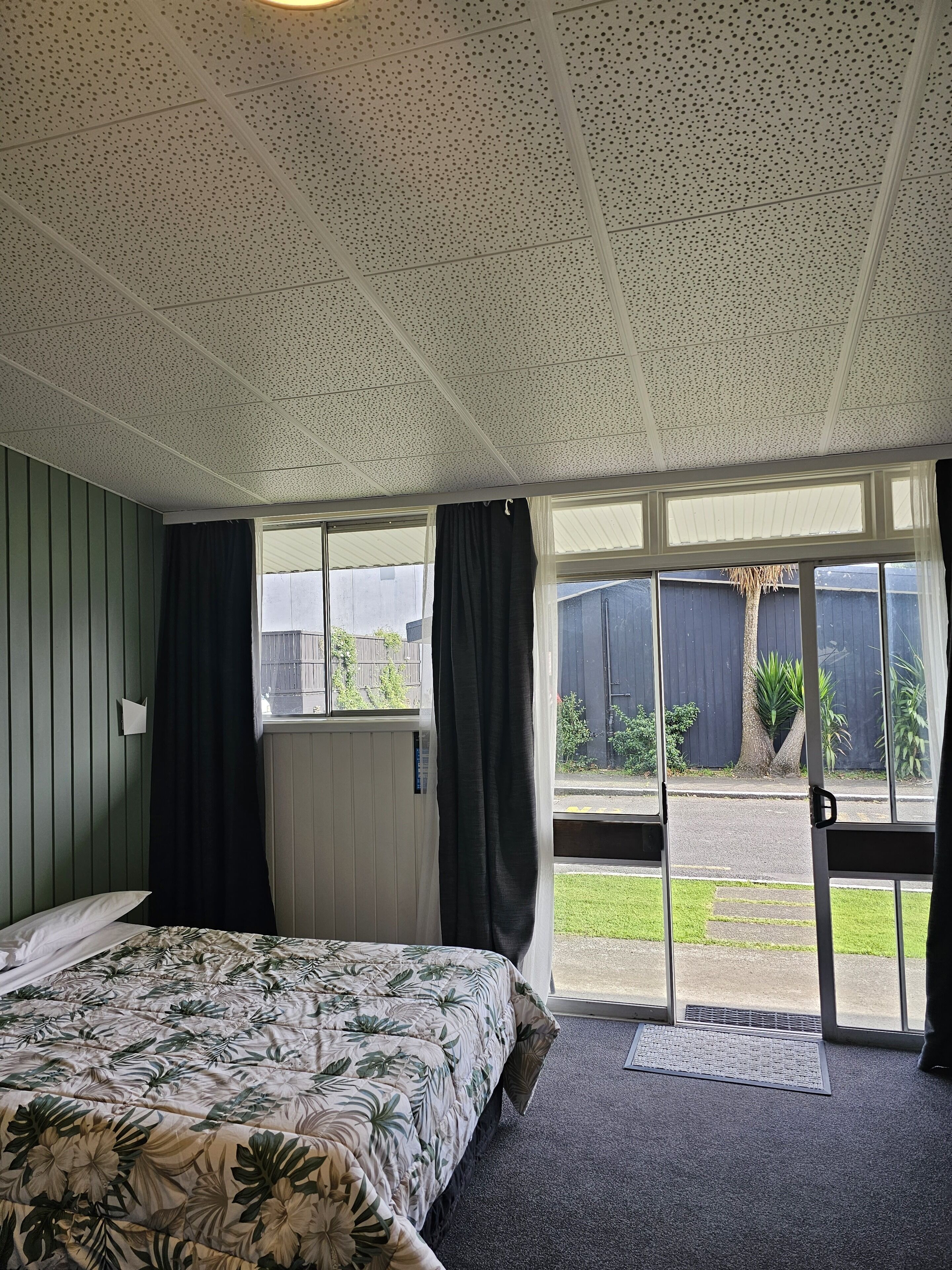 Una habitación con cama, ventana con cortinas y vistas al exterior.