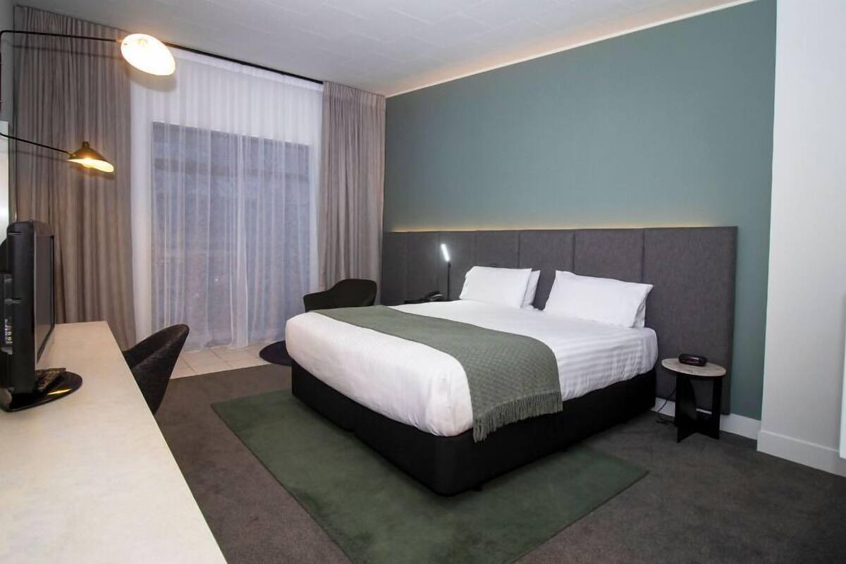 Een moderne hotelkamer met een groot bed, een bureau, een stoel en een klein tafeltje.