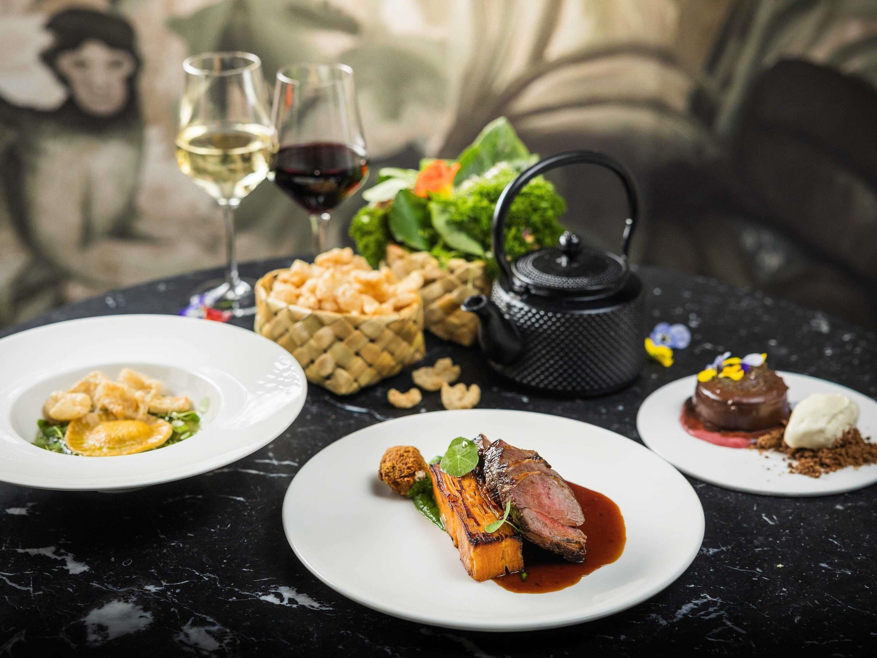 A table set with plates of food, glasses of wine, and a teapot.