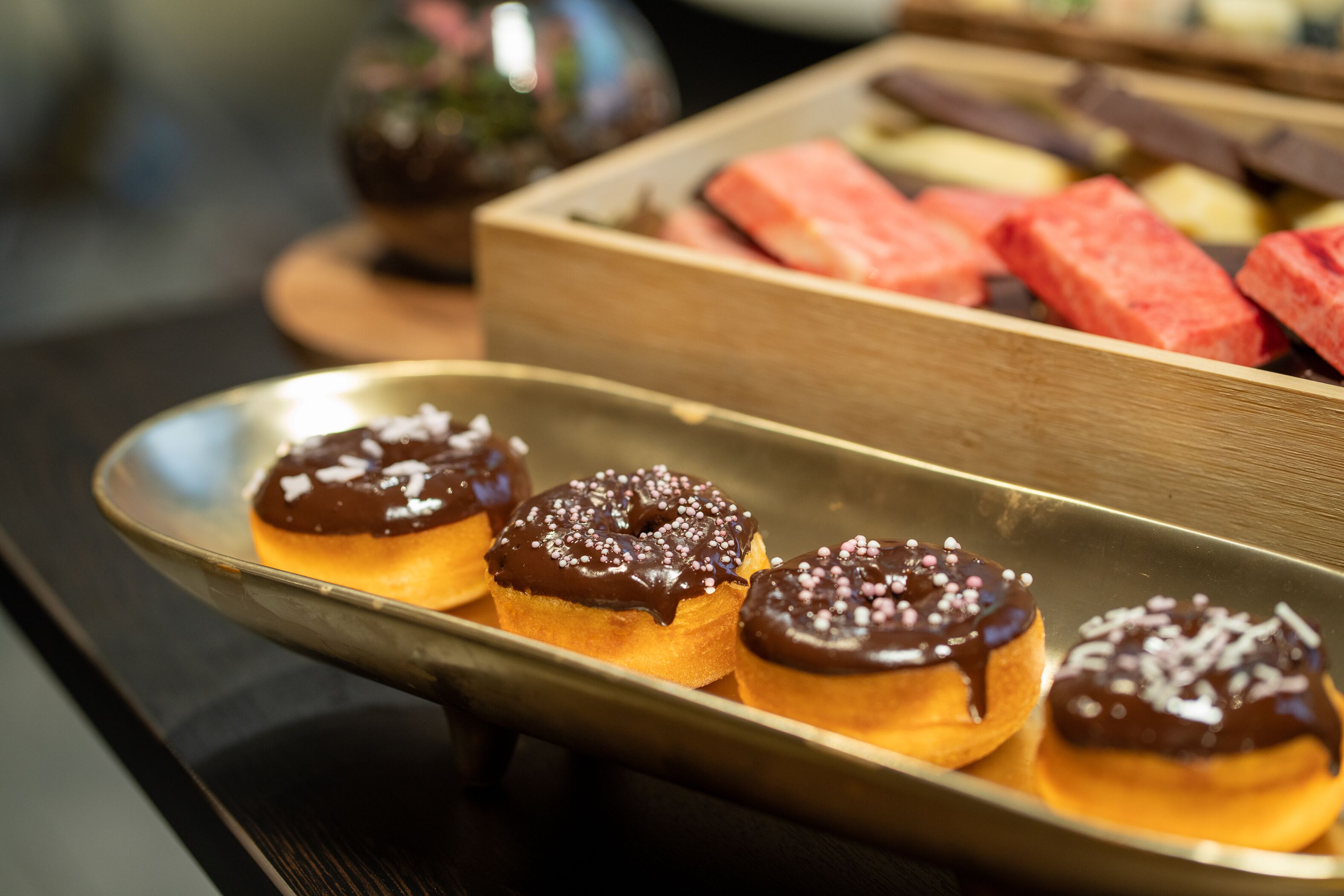 Una bandeja de donuts glaseados de chocolate con chispas.