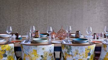 A dining table set with plates, glasses, and cutlery, surrounded by chairs with floral upholstery.
