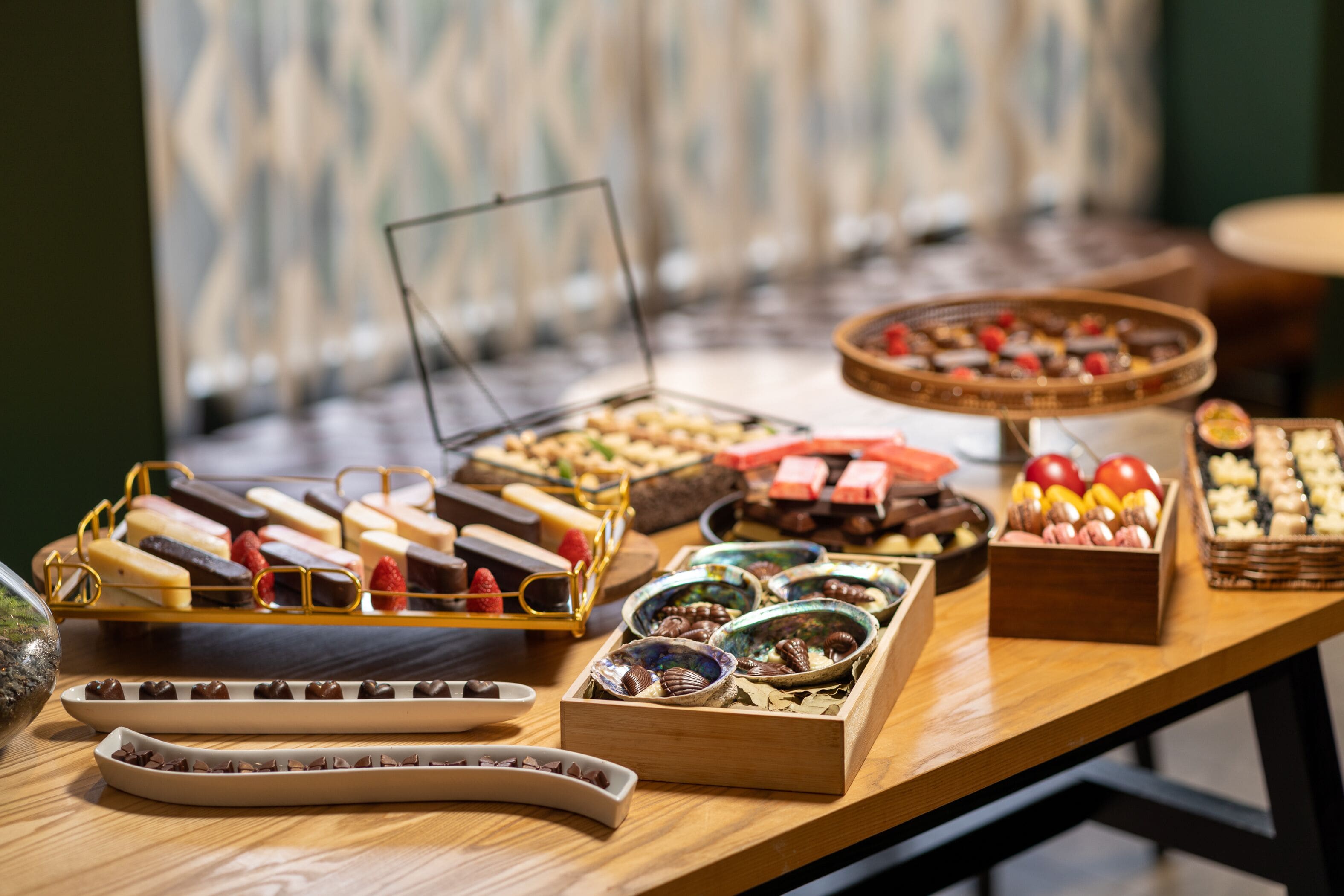 Une table de buffet proposant une variété d’aliments, notamment des chocolats, des fruits et des pâtisseries.