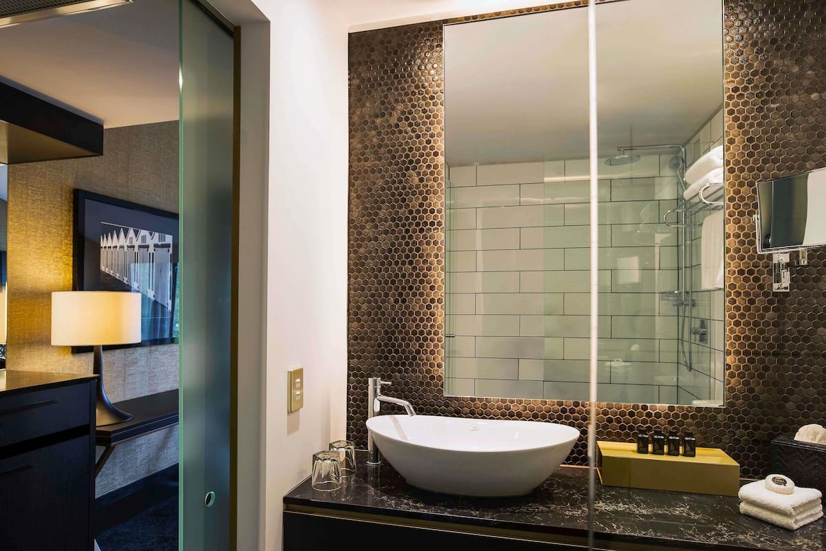 A modern bathroom with a large mirror, a white sink, and a glass shower enclosure.